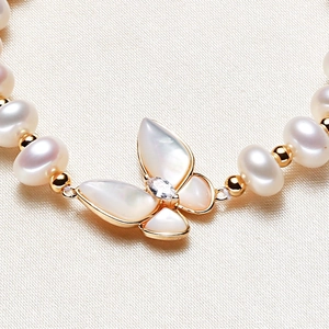 Elegant gold bracelet featuring a butterfly shell pendant and freshwater pearls on silk