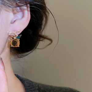 Detailed close-up of a pineapple earring with amber gemstone and Summer script