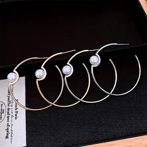 Minimalist gold and silver hoops with white pearls on a black jewelry box display