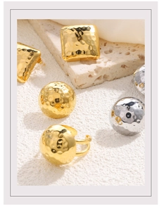 Detailed close-up of hammered 18K gold and silver geometric stud earrings on a stone base