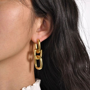 Close-up of model wearing triple-linked gold chain earrings in a stylish 18k gold finish