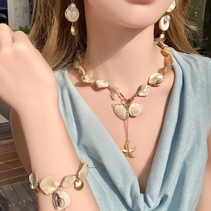 Close-up of shell and starfish pendant necklace set with gold metallic accents