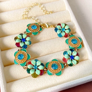 Detail of vintage gold flower bracelet with green enamel and colorful rhinestones