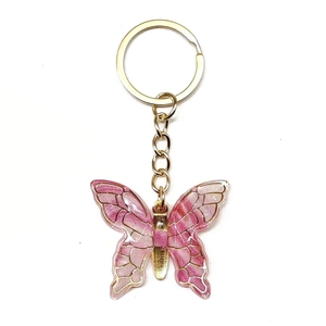 Detail of pink gradient butterfly keychain with gold-plated edges and metal keyring
