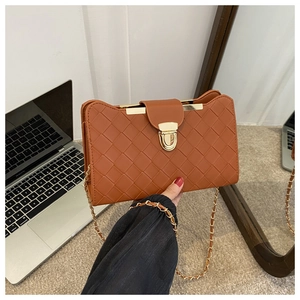 Detail of brown woven leather texture with gold metal lock and chain strap on shoulder bag