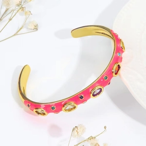 Macro shot of pink enamel cuff bracelet with colorful zircons and golden interior