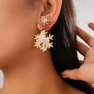Close-up of a reindeer and snowflake earring with rhinestones on a model's ear