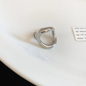 Detailed view of silver irregular organic metal ring on white aesthetic ceramic plate