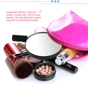 Close-up of portable round magnifying makeup mirror inside a pink cosmetic bag with brushes