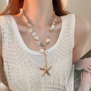 Detail view of beach style beaded necklace with golden starfish and natural seashell charms