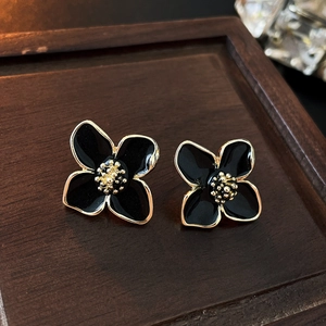 Makroaufnahme süßer Blumen-Ohrstecker mit schwarzen Blüten und vergoldeten Details