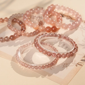 Macro shot of assorted pink strawberry quartz beaded bracelets on warm white paper