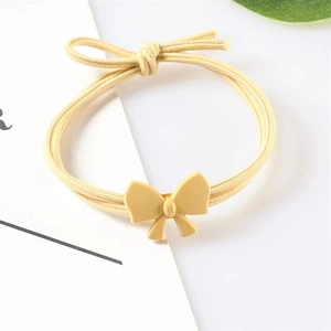 Elastic light yellow hair tie with a sweet resin bow accent on a clean white background