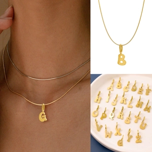 Detail view of gold and silver initial necklaces with snake chains worn and displayed