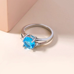 Detail of silver ring with round blue gemstone and small side cubic zirconia stones