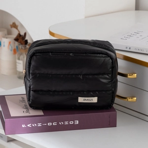 Quilted black puffer makeup bag with waterproof nylon and zipper on fashion book
