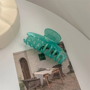 Detail of a large mint green hair claw clip with semi-transparent jelly texture and sturdy teeth