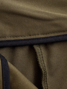 Close-up of olive green twill fabric with black trim and detailed stitching on wide leg pants