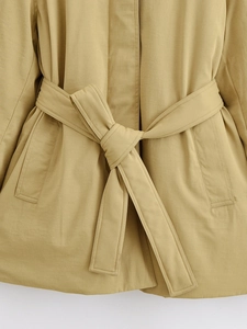 Detail of waist belt with bow knot and pocket stitching on khaki cotton jacket