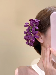 Détail d'une pince à cheveux fleur en tissu violette portée sur une coiffure en chignon