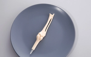 Creative bone-shaped ballpoint pen on a gray plate featuring realistic bone texture details