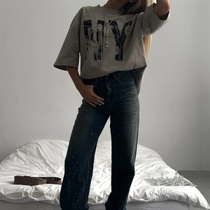 Détail du t-shirt gris vintage imprimé NY et jean bleu orné de strass brillants