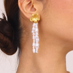 Orecchini a fiore dorati con nappe di perle barocche indossati da una modella