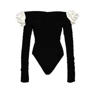 Detail of black off-shoulder bodysuit featuring white floral accents and ruched fabric texture