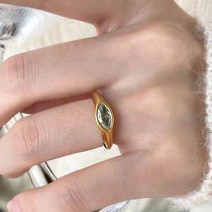 Macro shot of marquise-cut zircon ring in gold finish on a finger with knit background