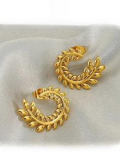 Macro shot of gold-plated titanium steel wheat ear earrings on silk fabric texture