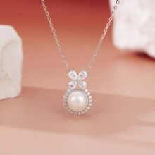 Detailed view of silver necklace with white pearl pendant and clover zircon stones