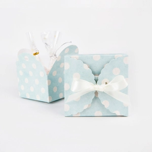Detail of blue polka dot paper gift box with white ribbon bow and wavy edge design