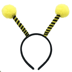 Detail of a funny bee costume headband featuring large yellow pom-pom antennae for parties