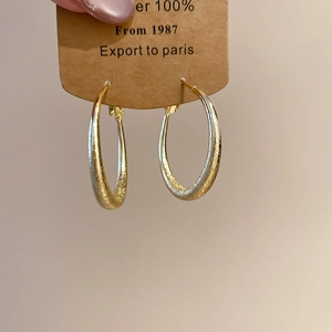 Détail macro de boucles d'oreilles rondes dorées mates au design élégant et minimaliste