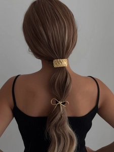 Detail of golden irregular textured hair cuff and bow-knot hair tie on model ponytail