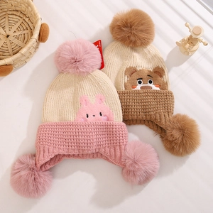 Detail of knit winter hats with pom-poms featuring pink rabbit and brown bear designs