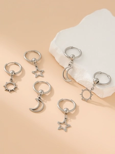 Macro detail of stainless steel earrings with sun moon and star charms on stone surface