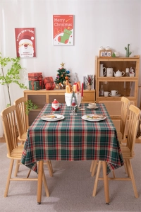 Close-up of festive red and green plaid tablecloth with tassel fringe on a wooden table