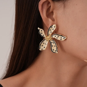 Gros plan détaillé de boucles d'oreilles fleurs crème à pois noirs avec pistils dorés