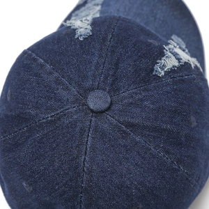 Detailed top view of a dark blue denim baseball cap featuring distressed textures and top button