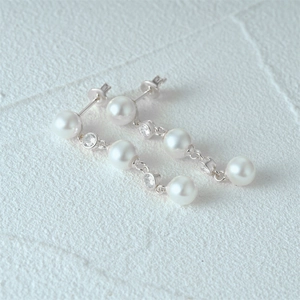 Macro detail of S925 silver drop earrings with triple pearls and sparkling zircon accents