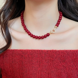 Macro view of dark red beaded necklace featuring a gold ring clasp with pavé crystals