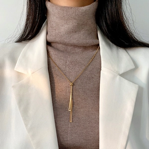 Detail of 18k gold plated titanium steel necklace with geometric tassel on a model