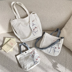 Set detallado de tres bolsos de lona blanca con estampados de conejos y correas grises