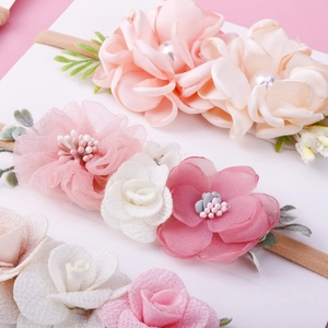 Detail of three floral baby headbands with satin flowers and pearl accents