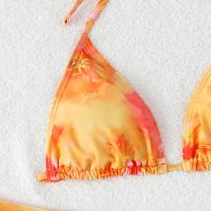 Detail of triangle bikini top with orange floral print and ties on white faux fur