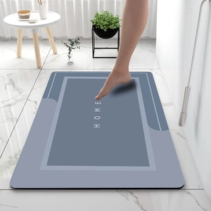 Minimalist blue diatomaceous mud bath mat with white HOME text in a modern bathroom