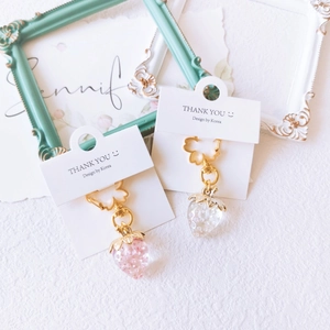 Pink and clear resin strawberry keychains with golden metal rings on white background