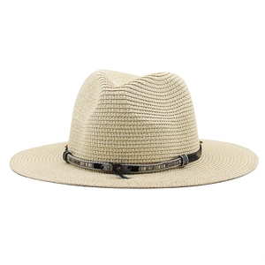 Close-up of woven straw hat with feather detail and decorative strap on a white background