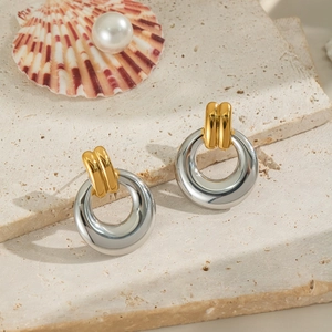 Detailed view of two-tone geometric hoop earrings on a stone slab with pearl accents